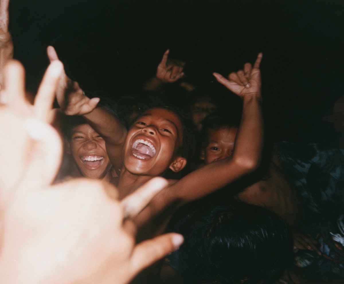 Children laughing and reaching toward the camera, lit by flash at night
